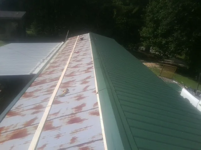 Old rusted panels beside newly installed green metal roofing — Wind Damage Roof Repair by Roofing Brothers in Thompsons Station