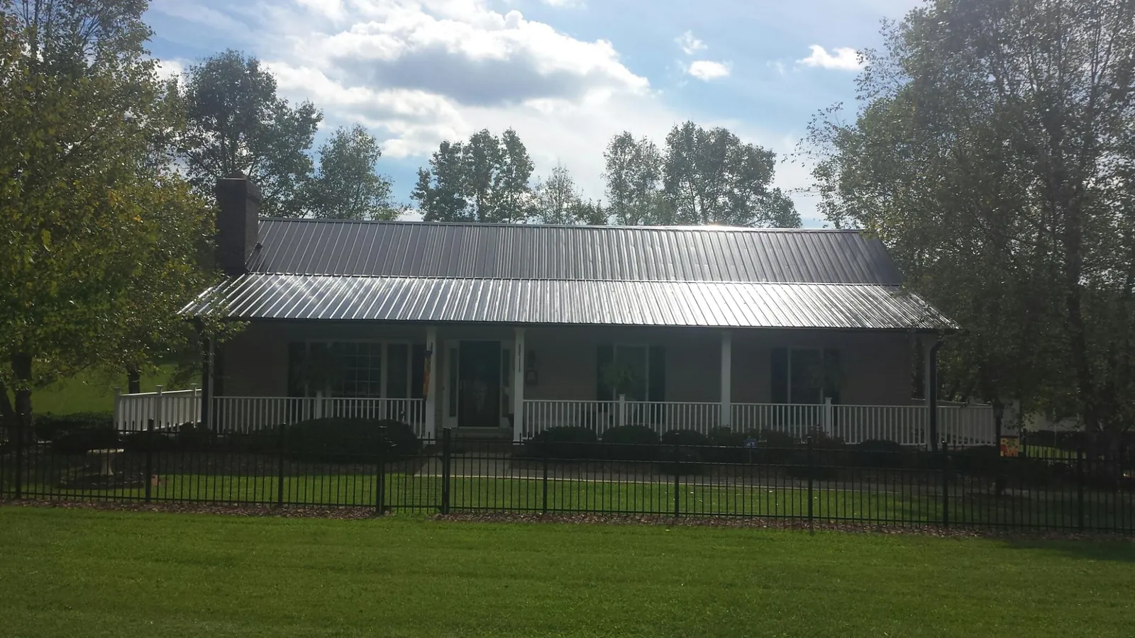 Gray metal roof on a brick ranch with a full width front porch — Gutter Guard Installation work by our crew in Thompsons Station