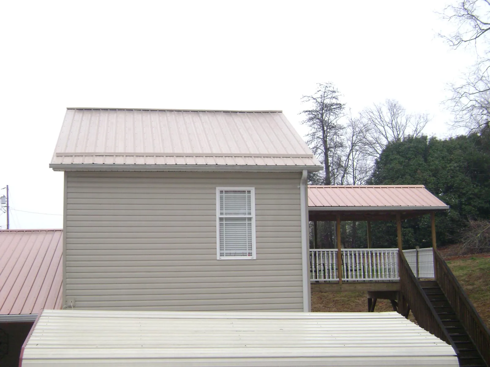 Tan metal roofs on a two story addition and attached porch, from a Roof Replacement job in Thompsons Station