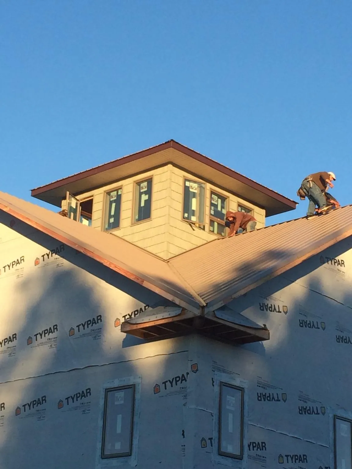 Roofers working around a rooftop cupola on a new metal roof at sunset — Roof Waterproofing in Thompsons Station by Roofing Brothers